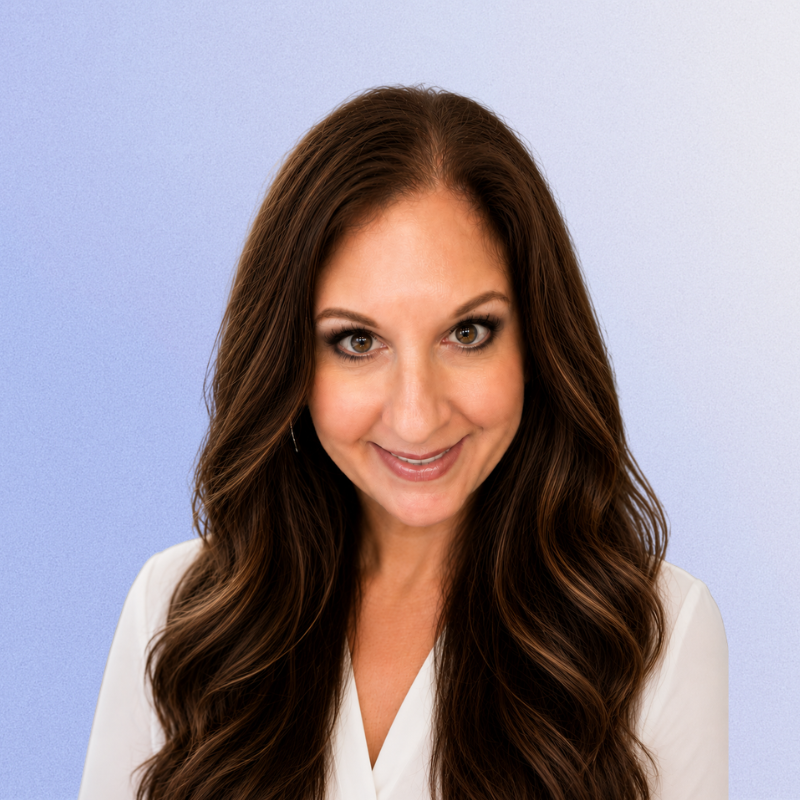 Smiling woman with long brunette hair in a white blouse.