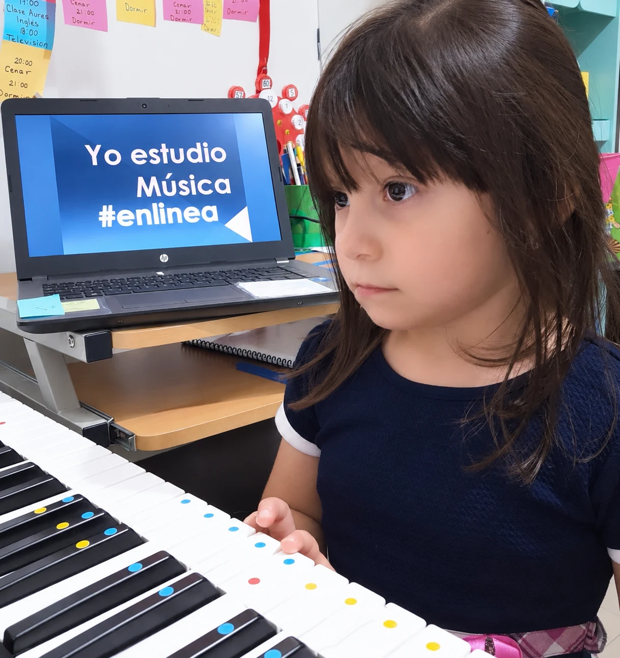 Niña al teclado con clase en pantalla