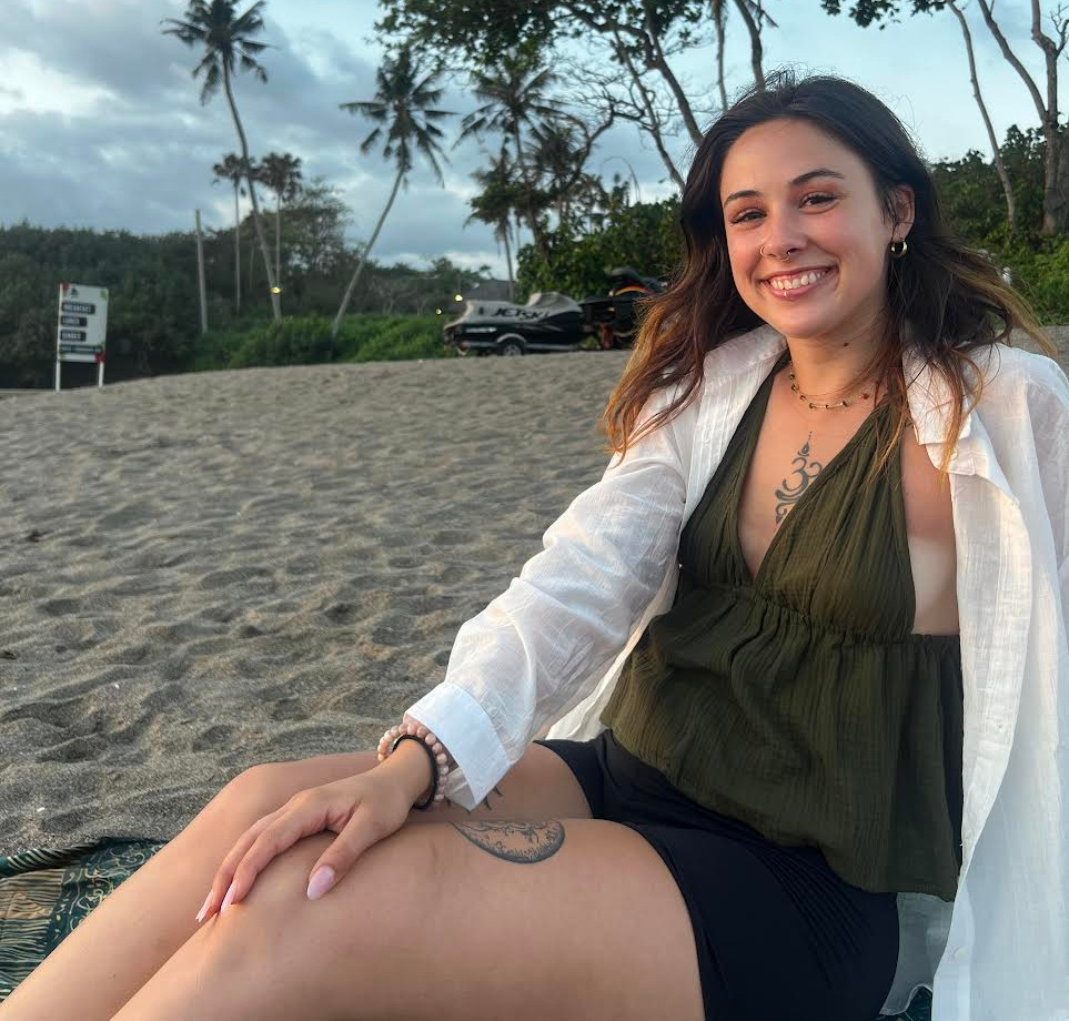 Woman smiling on a beach near a boutique yoga studio.