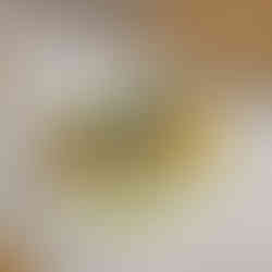 A colorful open-faced sandwich on a white plate, topped with orange spread, sliced cucumber, and green herbs, with a drizzle of green oil.