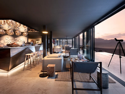 Interior of Sossusvlei Desert Lodge in Namibia at sunset, featuring minimalist eco-luxury design with panoramic desert views and a modern open-air bar.