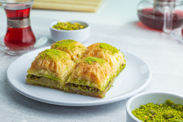 Four squares of pistachio baklava on a white plate.