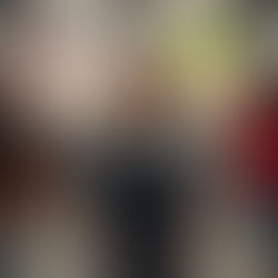 Image of a child with short hair, wearing a blue shirt and jeans. They are facing a busy blurred environment of many people. 