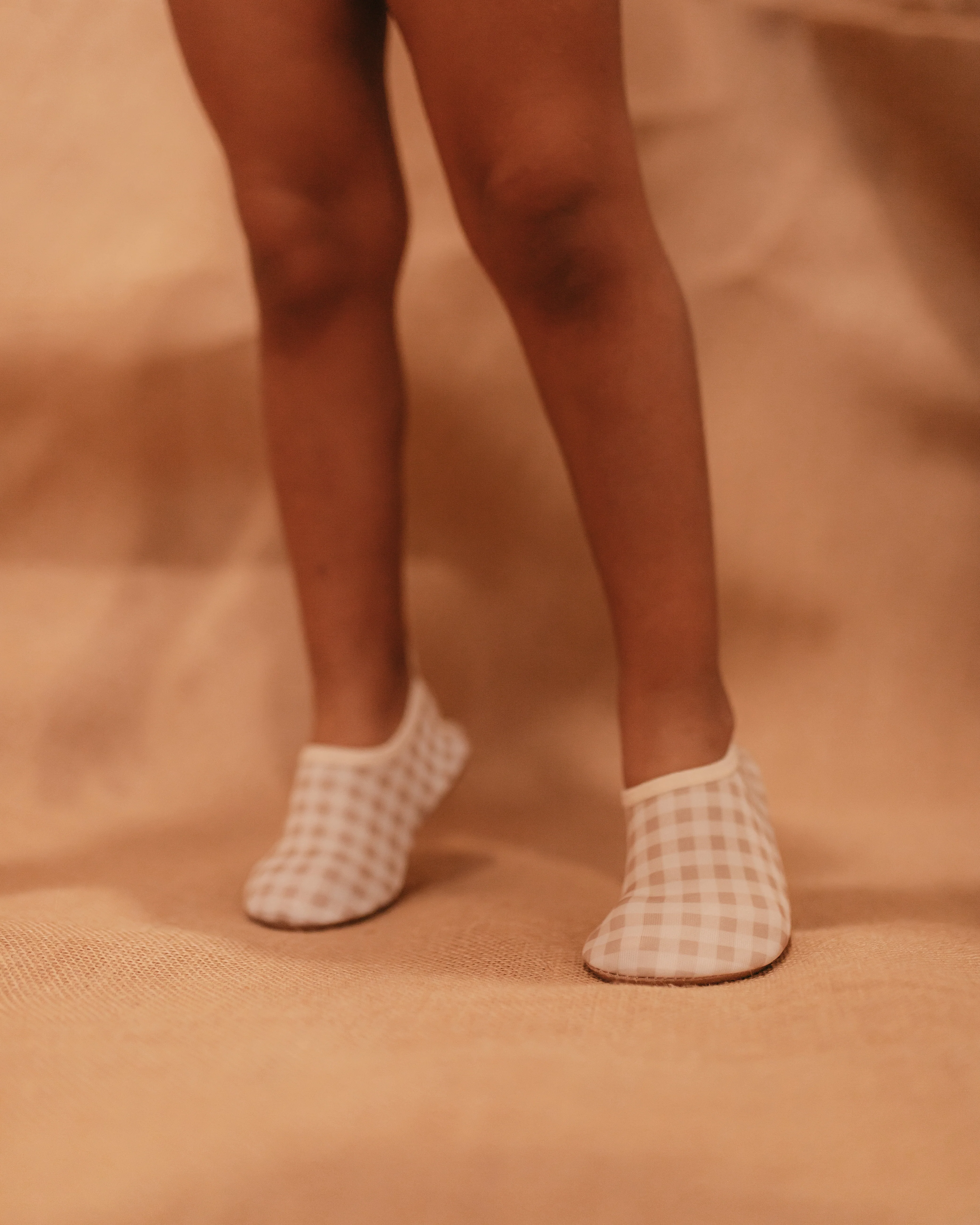 A girl wearing beige gingham swimming shoes