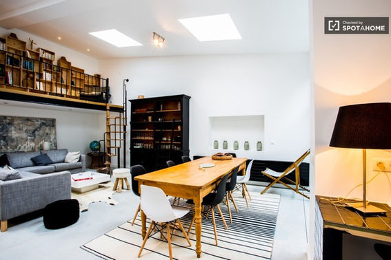 La salle à manger se situe à l'arrière de l'ancien atelier, à côté d'une cour intérieure. Les grandes fenêtres laissent entrer la lumière naturelle et offrent une vue sur l'espace extérieur.