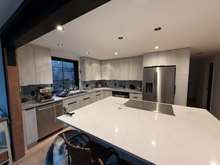 Modern kitchen remodel with new cabinets, island, appliances, and large window.