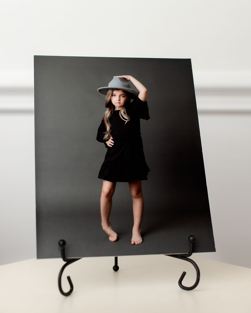 Portrait of a 7 year old girl in a black dress set in an easel.