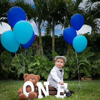 Baby boy in a gray suit surrounding for balloons