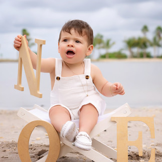 bABY BOY IN THE BEACH HOLDING A LETTER
