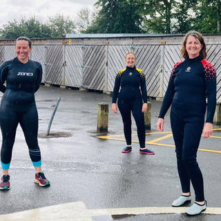 4 women smiling in their wetsuits