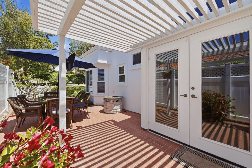 White pergola over patio with outdoor seating area.