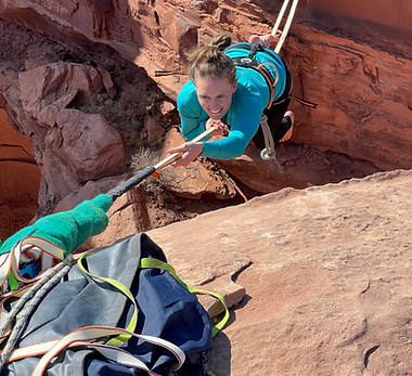 A woman crawls across a highline during a highline course with Elevate Outdoors in Moab, Utah.