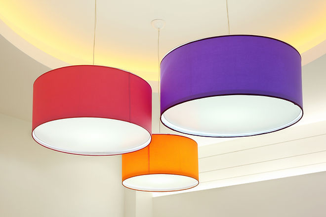 Purple, red and orange round stylish lampshades hang from ceiling.