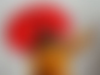 Woman in yellow rain coat, smiling with joy whilst holding a red umbrella