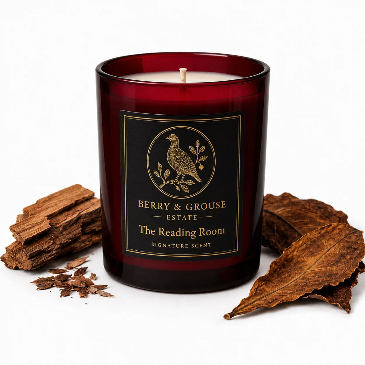 Berry & Grouse The Reading Room candle in deep red glass with black and gold label, styled on a white background with cedarwo