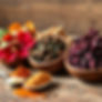 dried Hibiscus, moringa and ginger in wooden bowls on a line behind and powders in spoons