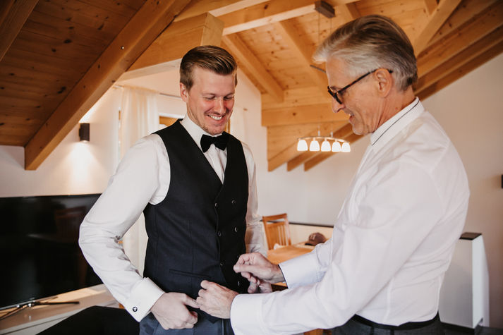 Brautvater hilft Bräutigam beim Anziehen
