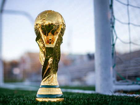 World Cup trophy next to futbol goal. Photo by My Profit Tutor Unsplash
