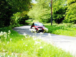 a red car driving on a sunny day
