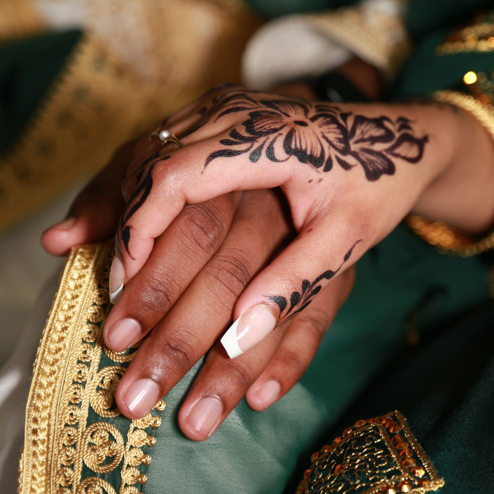 les mains de mariés avec henné manucure et tenue verte / gros plan