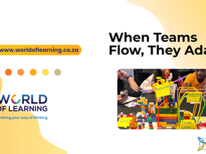 When teams flow, they adapt. Photo of a group sitting at a table with a LEGO construction with the words Ambitious, Focus, Team Work, and Productive written on Post-It notes