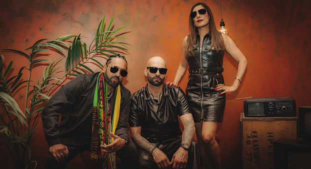 Artists in a warm, moody room with plants, creating a gritty “Fiyah” music video scene.
