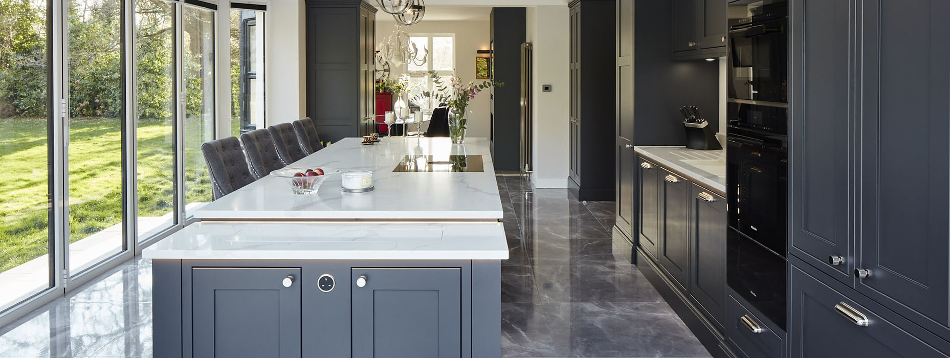 Blue Stoneham bespoke kitchen. In a classic Shaker style. Available from Somerville limited in Five Oaks Jersey. A luxury Stoneham kitchen designer in Jersey. It is a dark blue shaker style with white quartz worktops and chrome handles