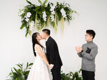 A couple kissing during an indoor wedding ceremony at The Ensora in Richmond, BC.