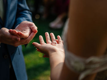 A Ring Warming Moment™ during a wedding ceremony, with a wedding band resting in the bride's hand before the exchange of rings