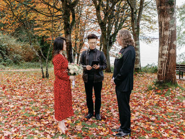 Couple sharing an intimate elopement ceremony in Stanley Park, Vancouver, BC surrounded by autumn trees.