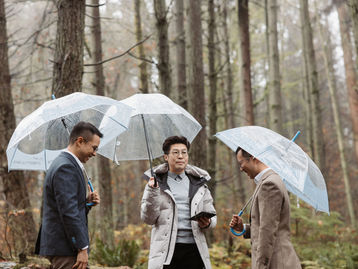 An LGBTQ couple and officiant during an inclusive outdoor wedding ceremony at Stanley Park in Vancouver.