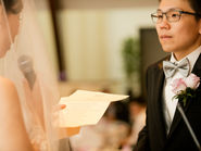 A bride reading her vows during an intimate indoor wedding ceremony in Vancouver, standing with her partner and an officiant in a small micro wedding setting.