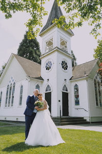 Bride and groom posing in front of Minoru Chapel’s main entrance on a sunny day.