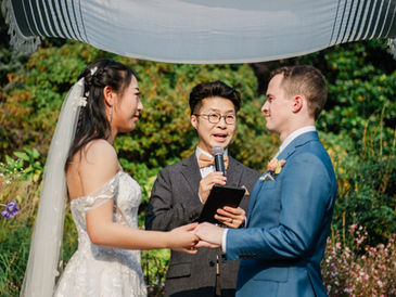 couple holding hands during a wedding ceremony with officiant speaking in an outdoor setting