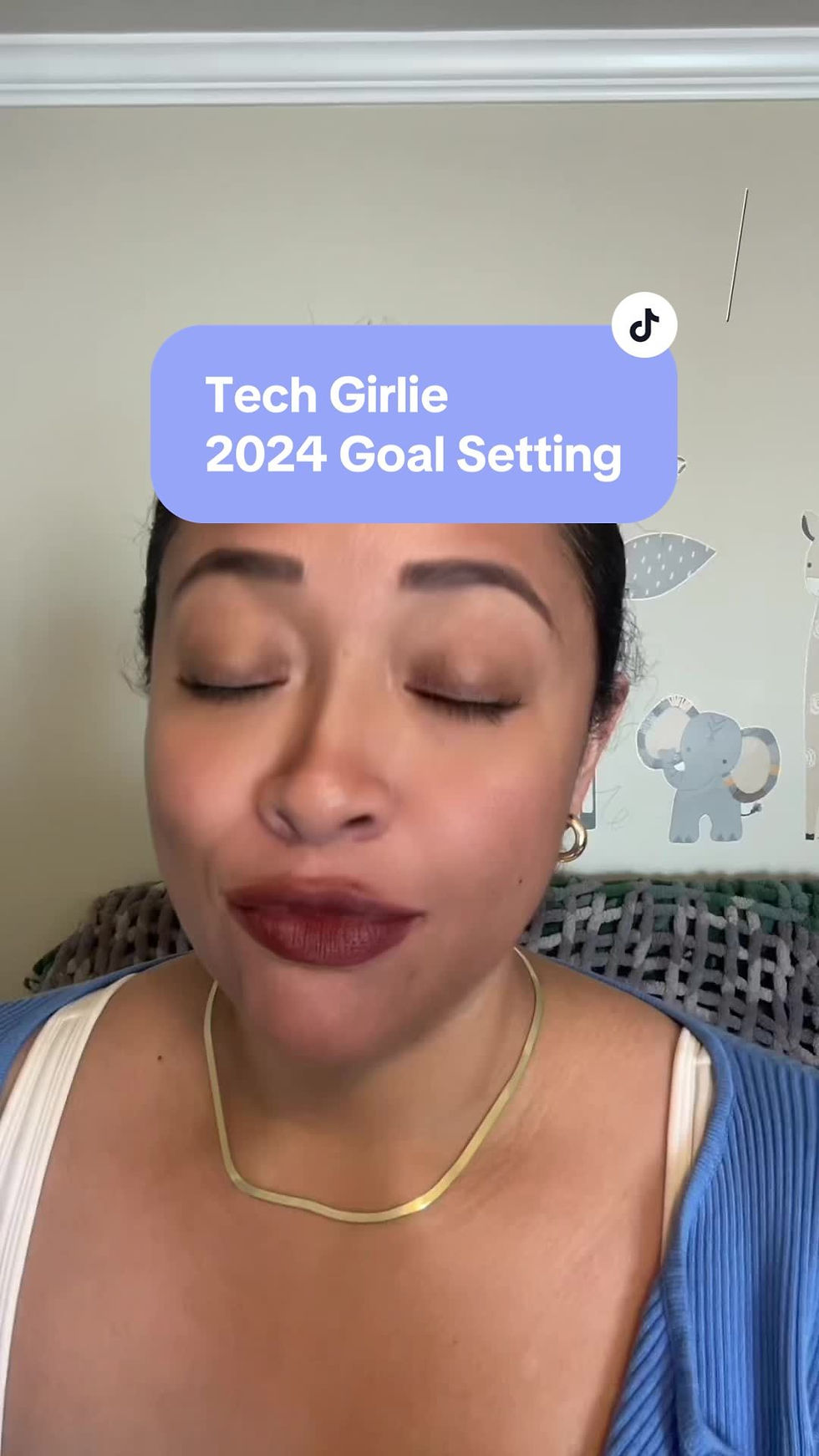 Person with eyes closed, wearing a blue sweater, in front of a nursery wall. Text reads: "Tech Girlie 2024 Goal Setting." Calm mood.