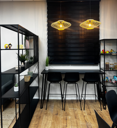 מסעדה מעוצבת עם שולחן בר, כיסאות שחורים ותאורה ייחודית, חלל פנים מודרני.