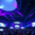 a summit in a huge building with light purple and white lights and big screens and a lot p