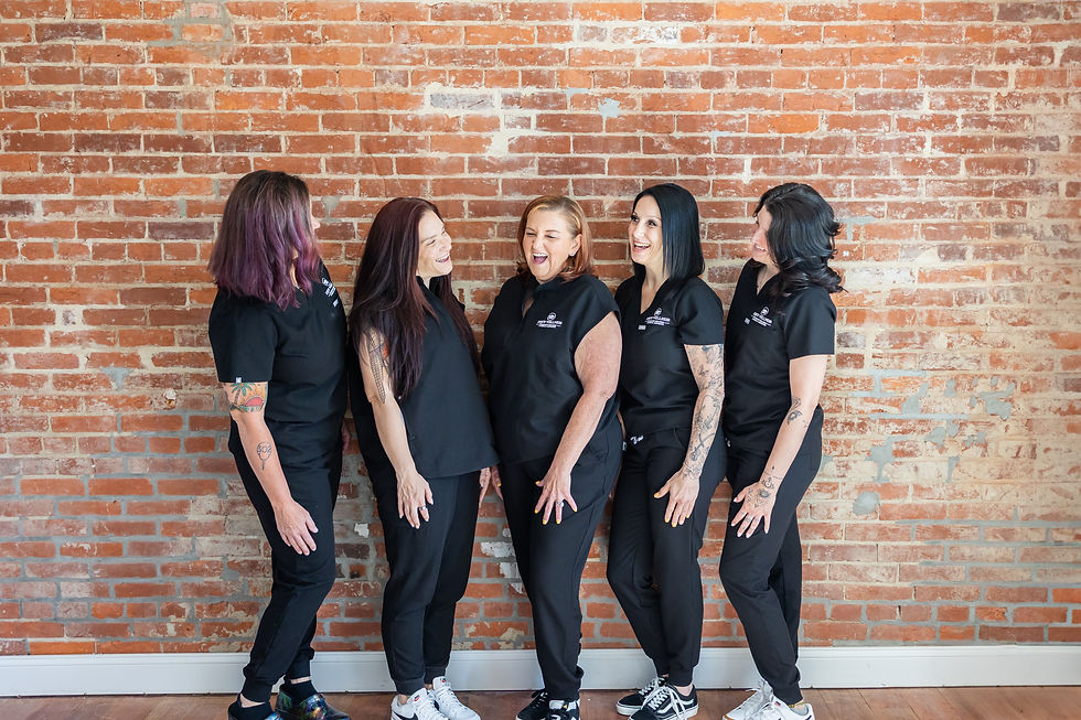 Joyce Bilski with her team laughing against a brick wall.