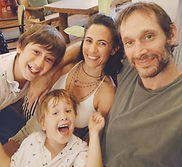 Smiling family of four posing for a selfie indoors.