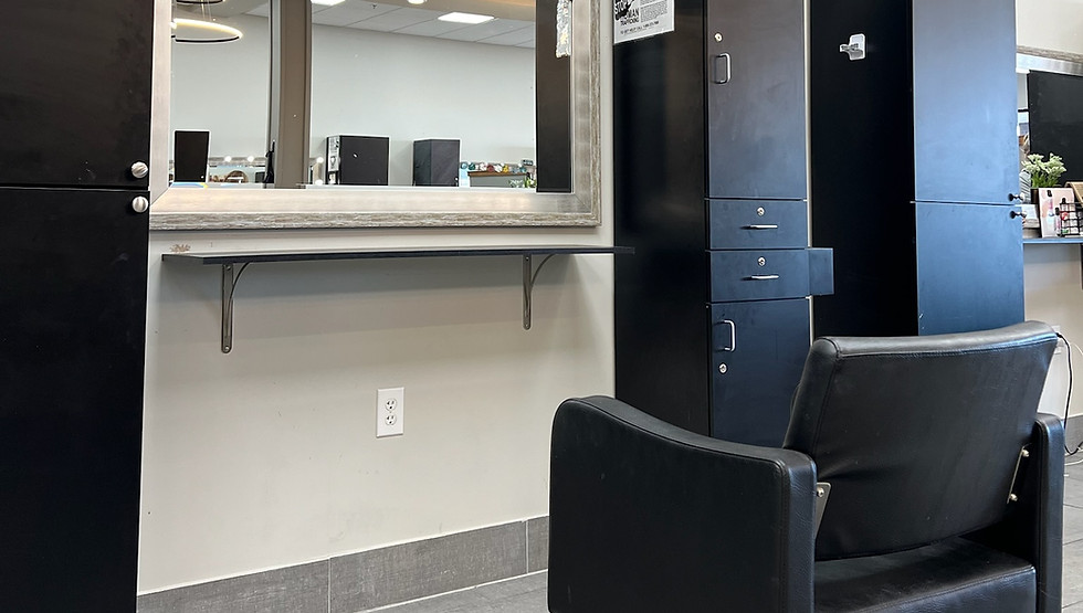 A chair in a space at Salon 190 next to storage shelving and a mirror in front of chair