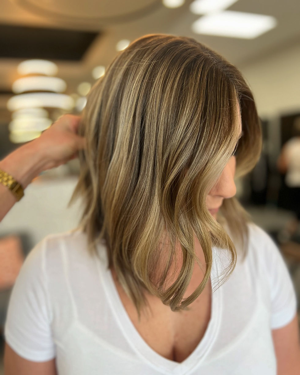 Woman with blonde balayage hair in a salon setting.