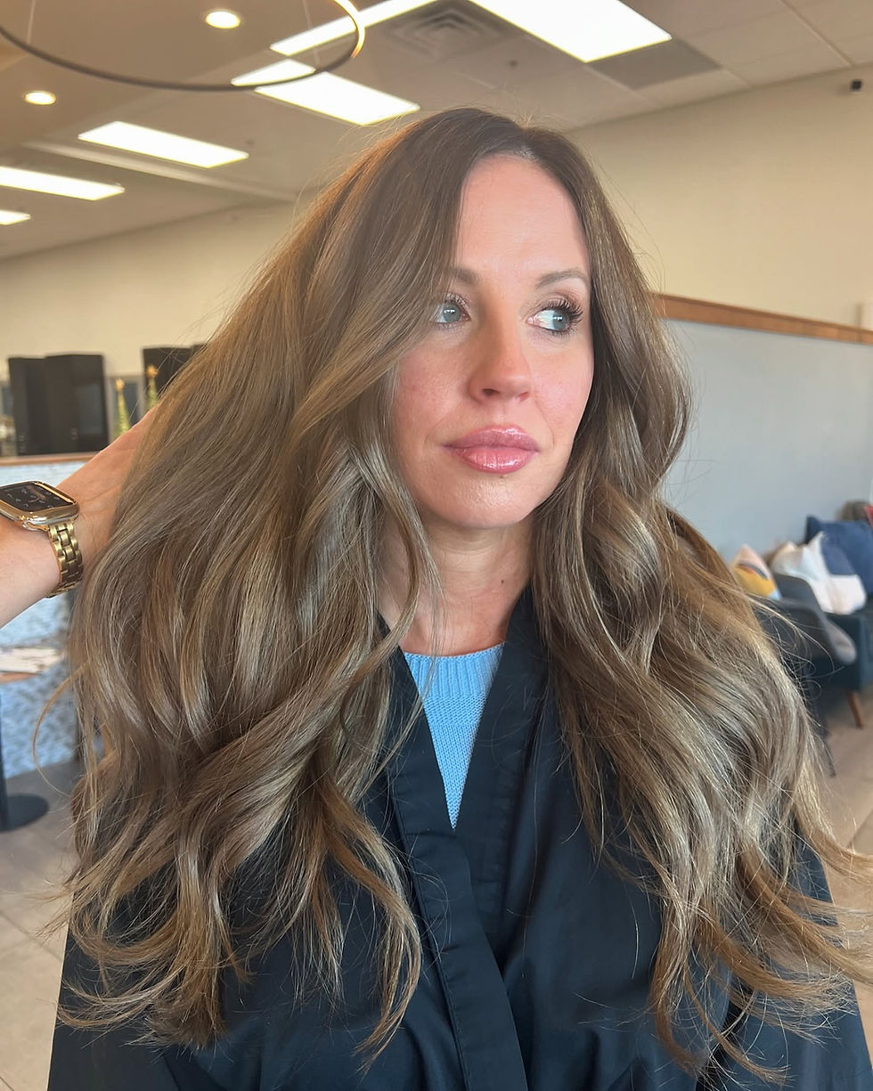 After cut, color and style of woman with long wavy light brown hair in a salon