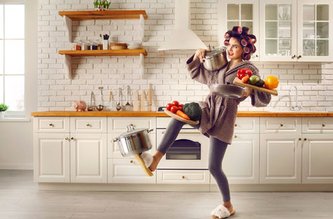 Woman balancing pots and vegetables in the kitchen, symbolizing the mental load and overwhelm of carrying it all alone.