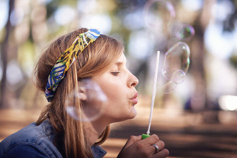 Woman blowing bubbles outdoors, symbolizing playfulness and reconnecting with the inner child.