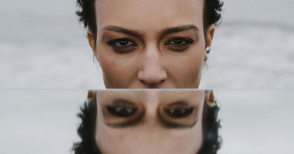 A woman's face cut by her own reflection upside down representing the fawn response altering an entire life