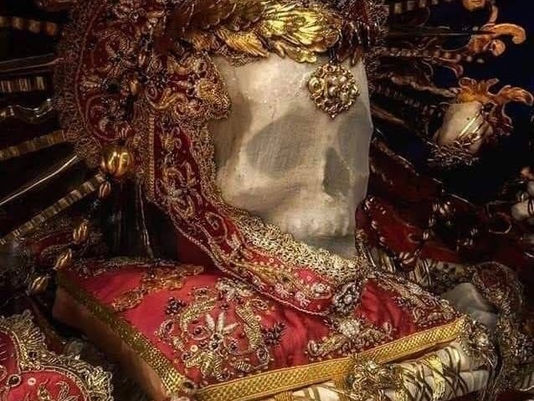 Картина на човешки череп, който е обсипан с накити и е поставен на богато обшита с мъниста калъвка със златни пискюли. Тази картина символизира структурата и стоицзмът на Сатурн докато човекът получи призвание за труда си.