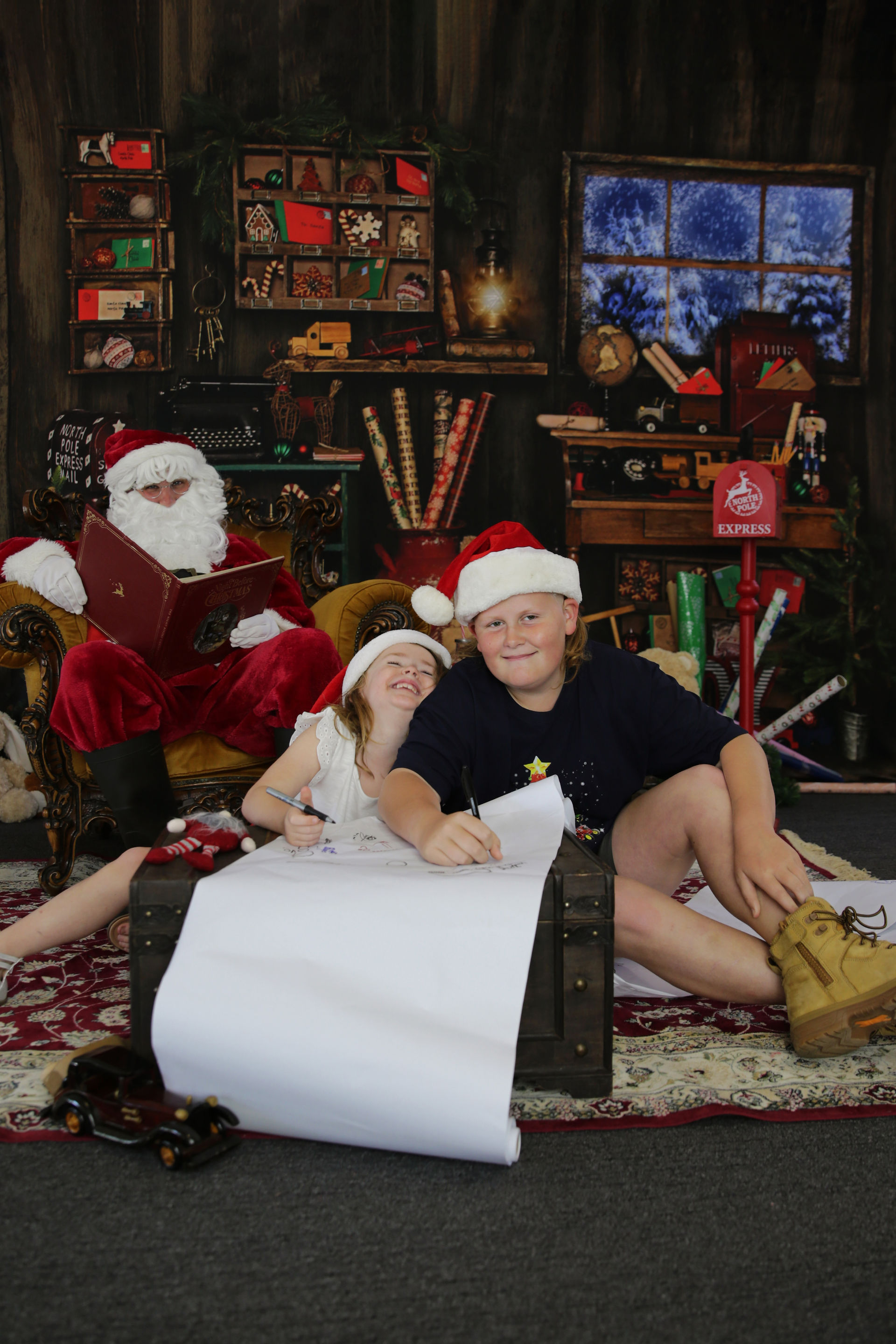boy and girl writing letter in front of santa