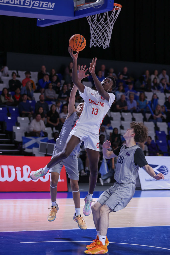 England U14 basketball player attempting a layup against Scotland during a Home Nations game.