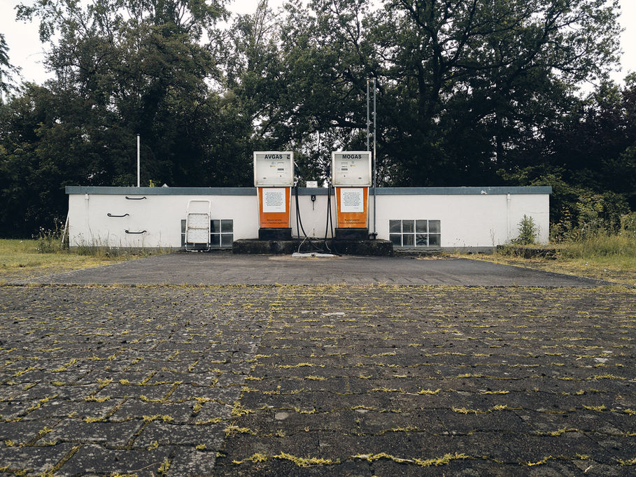 2 Zapfsäulen vor dem Gebäude eines Segelflugplatzes in trüber Wolkenstimmung