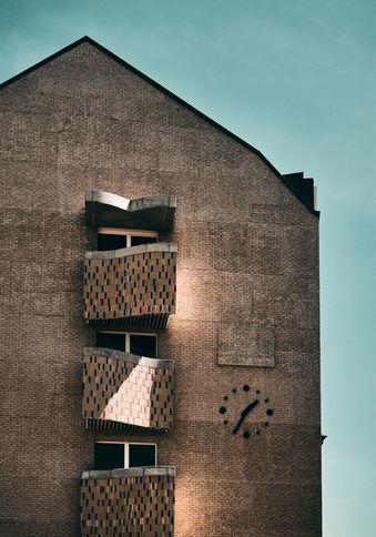 Außenansicht der Balkone und der Uhr des Riegelbaus im Bestehornpark in warm kalt Komplementär Stil